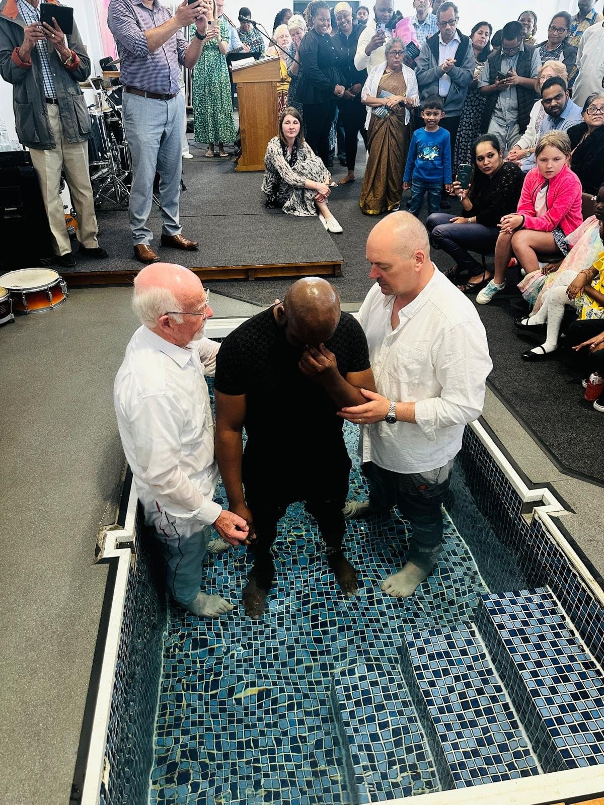 A baptism in the baptistry at King's Christian Centre, watched by the congregation