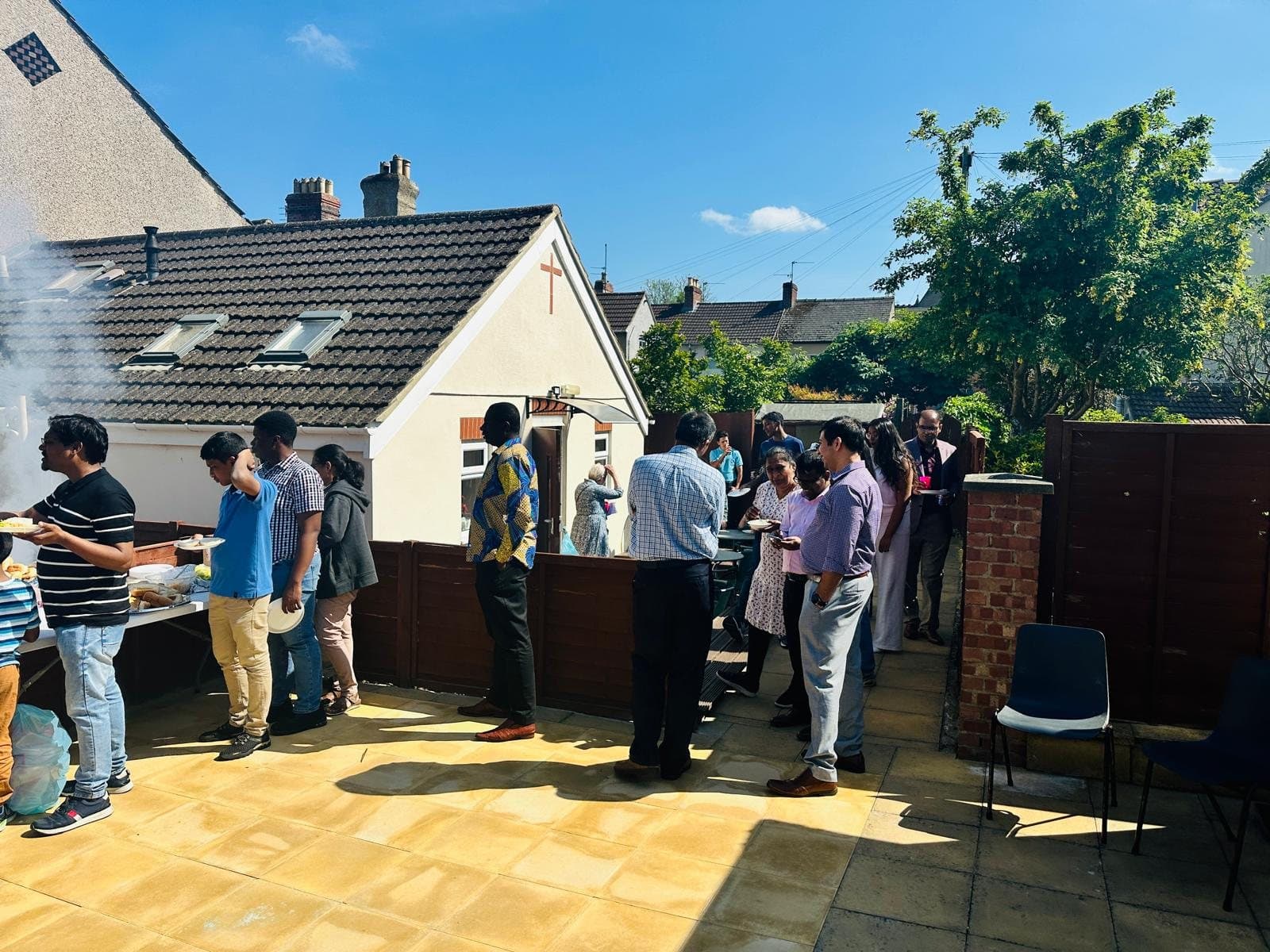 Church members talking and sharing food in the church garden on a sunny day